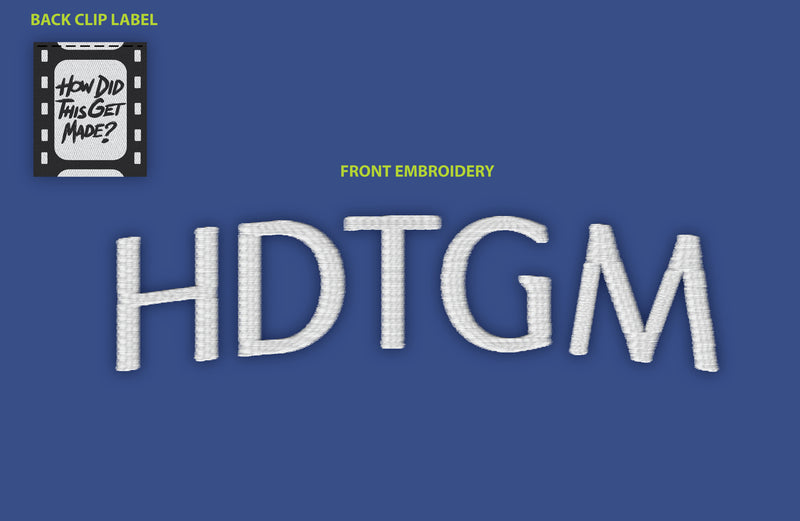 A royal blue background displaying the close-up embroidery details for the cap. The front embroidery features 'HDTGM' in bold, white, textured text. The back clip label is a black and white patch designed like a film strip, with the text 'HOW DID THIS GET MADE?' written in a handwritten-style font. 