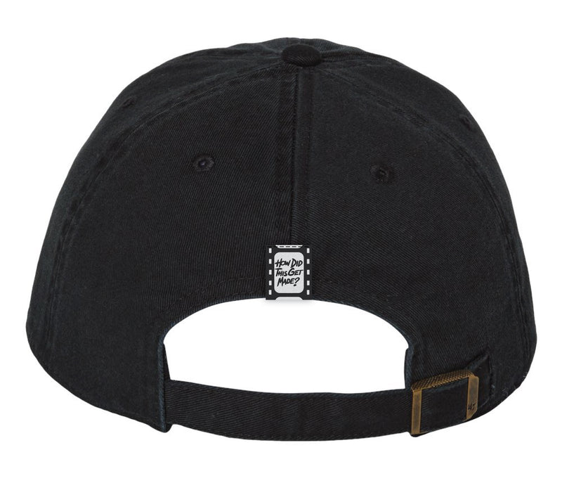 The black baseball cap viewed from the back. It features an adjustable strap with a brass buckle. A small black tag with white text reading 'HOW DID THIS GET MADE?' is sewn onto the back of the cap, resembling a film strip design.