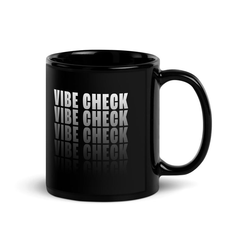 A black glossy coffee mug featuring bold white text that reads "VIBE CHECK" in a stacked, repeating pattern with a reflection effect at the bottom. The handle is on the right side, and the design is centered on the front of the mug.