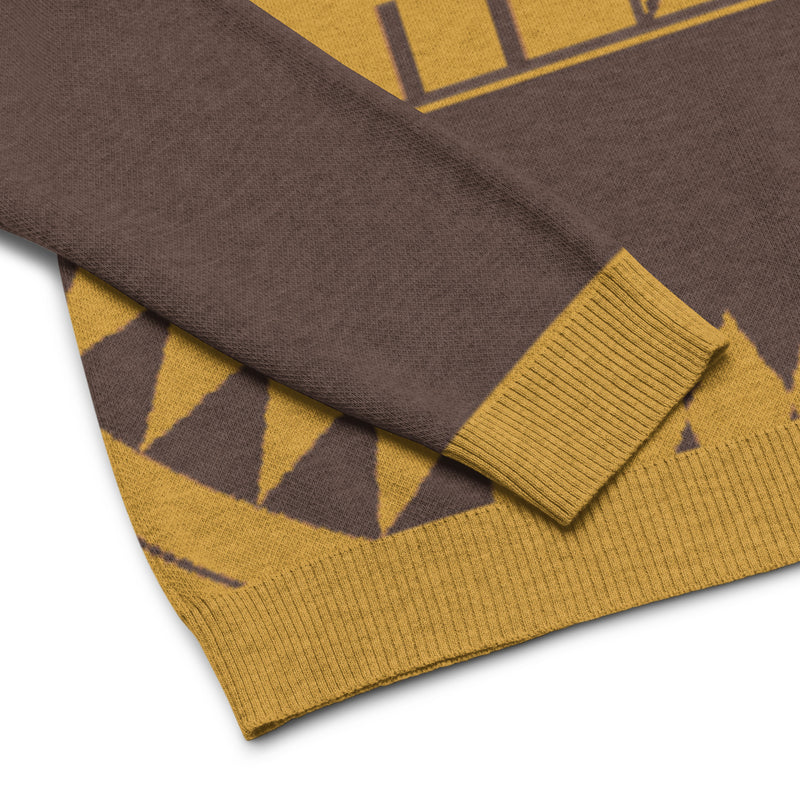 Close-up of a brown and gold patterned sweater, featuring a ribbed cuff and hem.