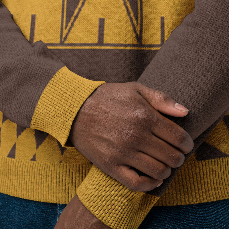 Close-up of two hands crossed, wearing a patterned brown and gold sweater.