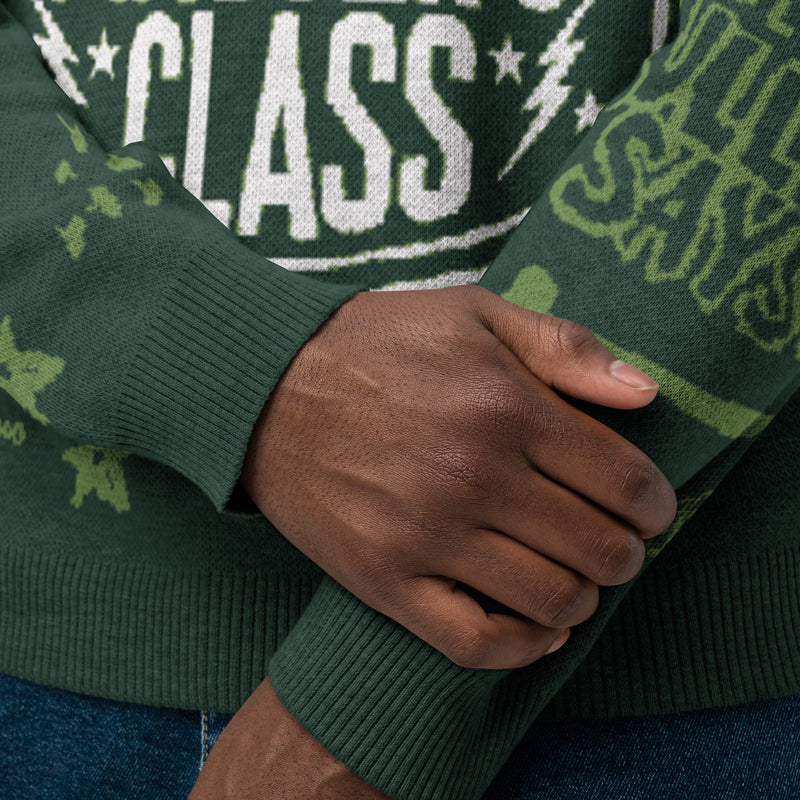 Close-up of hands crossing over a green sweater with a graphic designs, grafitti-style illustrations.