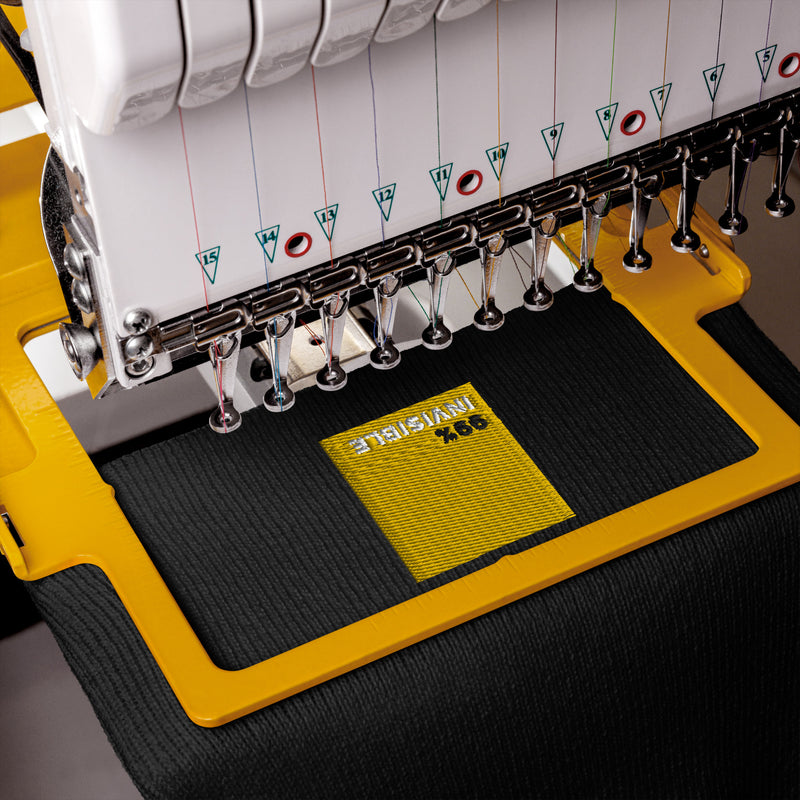 Close-up of black beanie hat with yellow square on a machine.