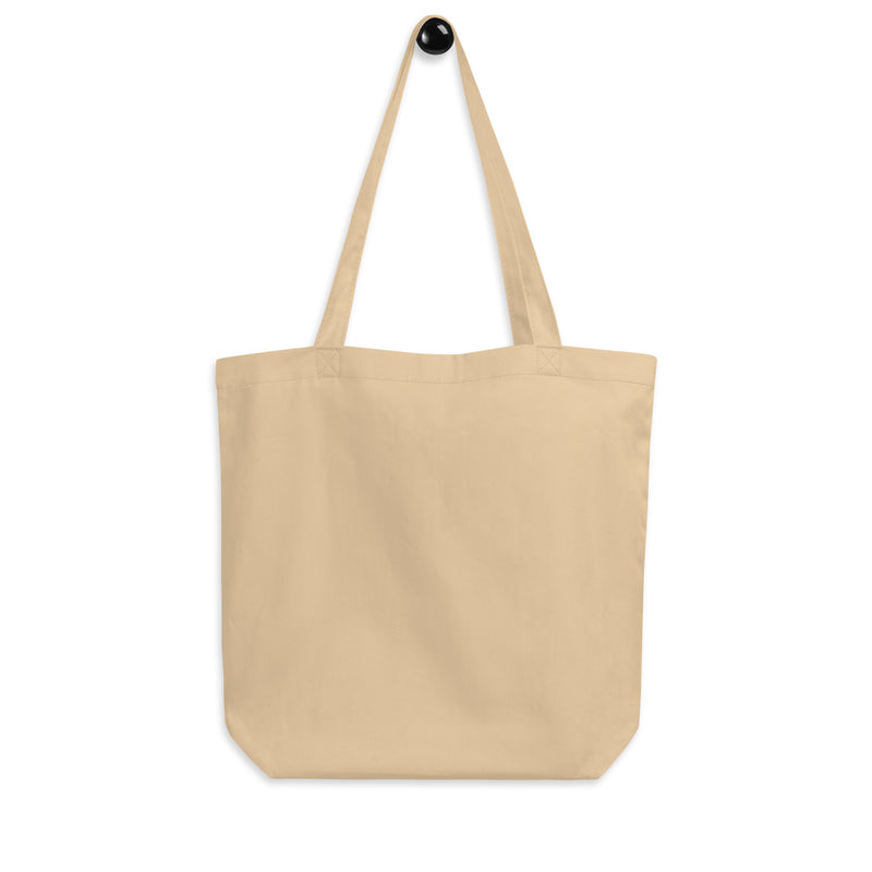 Backside of cream tote bag with handles hanging from a black hook, against a white background. 