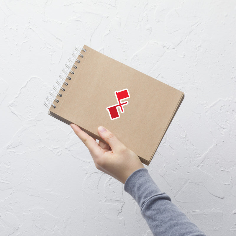 hand holding a spiral-bound notebook with a red and white logo on the cover against a textured white wall.