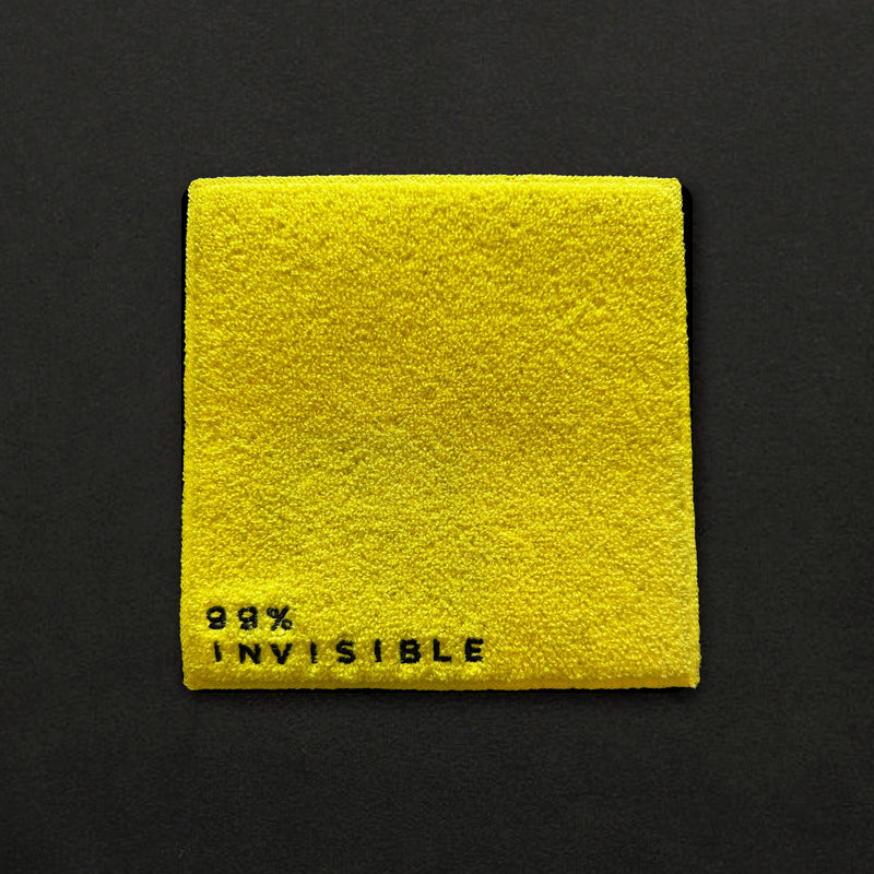 Close up of yellow square with the text '99% INVISIBLE' in black letters at the bottom.