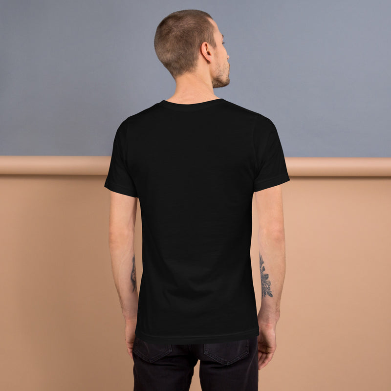 A man wearing a plain black t-shirt, viewed from the back. The t-shirt has a classic crew neck and short sleeves, with a clean, fitted look. The background features a neutral, two-tone setting.