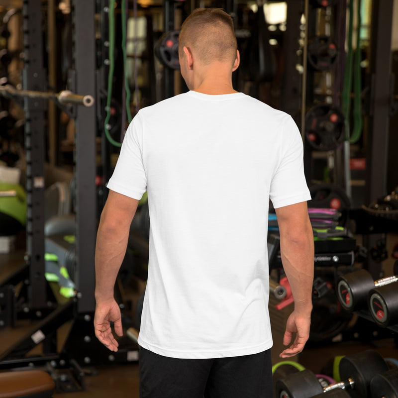 A man wearing a plain white t-shirt, viewed from the back, standing in a gym setting. The shirt has a snug fit, short sleeves, and a simple, clean design.