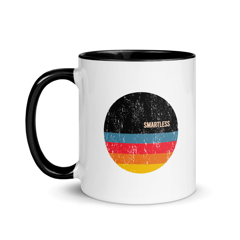 Black-handled mug with a circular design featuring the word 'SMARTLESS' and colorful horizontal stripes in blue, red, and yellow against a distressed black background.