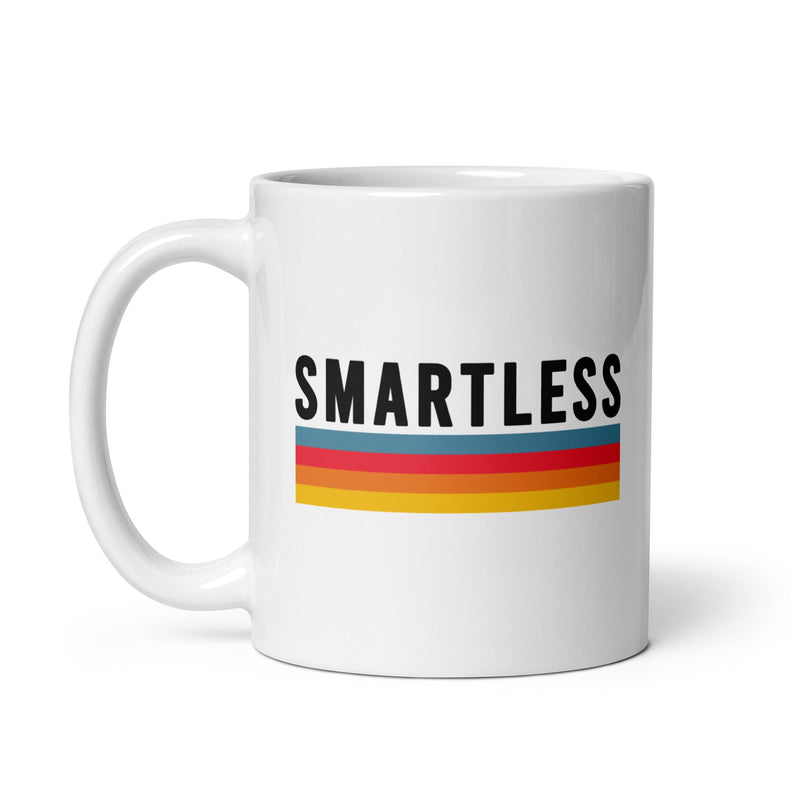 White ceramic mug with the word 'SMARTLESS' printed in black, featuring three horizontal stripes in blue, red, orange and yellow beneath it.