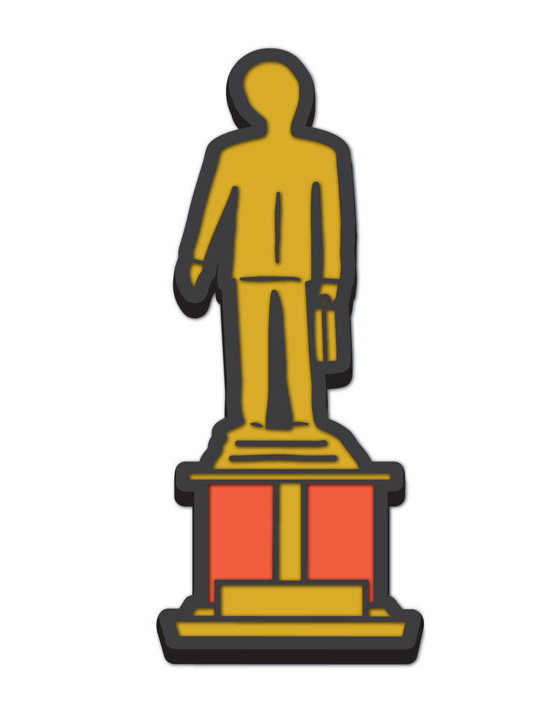 Rubber shoe charm of gold statue of a person standing on a pedestal holding a briefcase against a white background